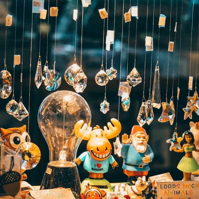 Bunte Figuren und Kristalle hängen an Schnüren in einem Schaufenster.